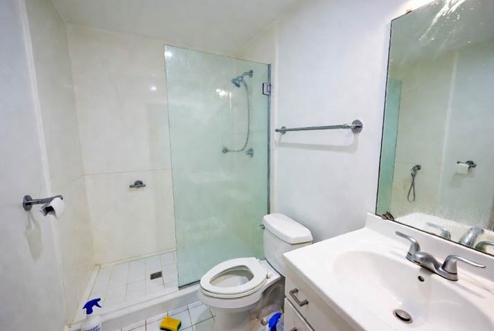 August Move-In Cleanings: A bright white bathroom with a glass walk-in shower, toilet, and vanity sink.